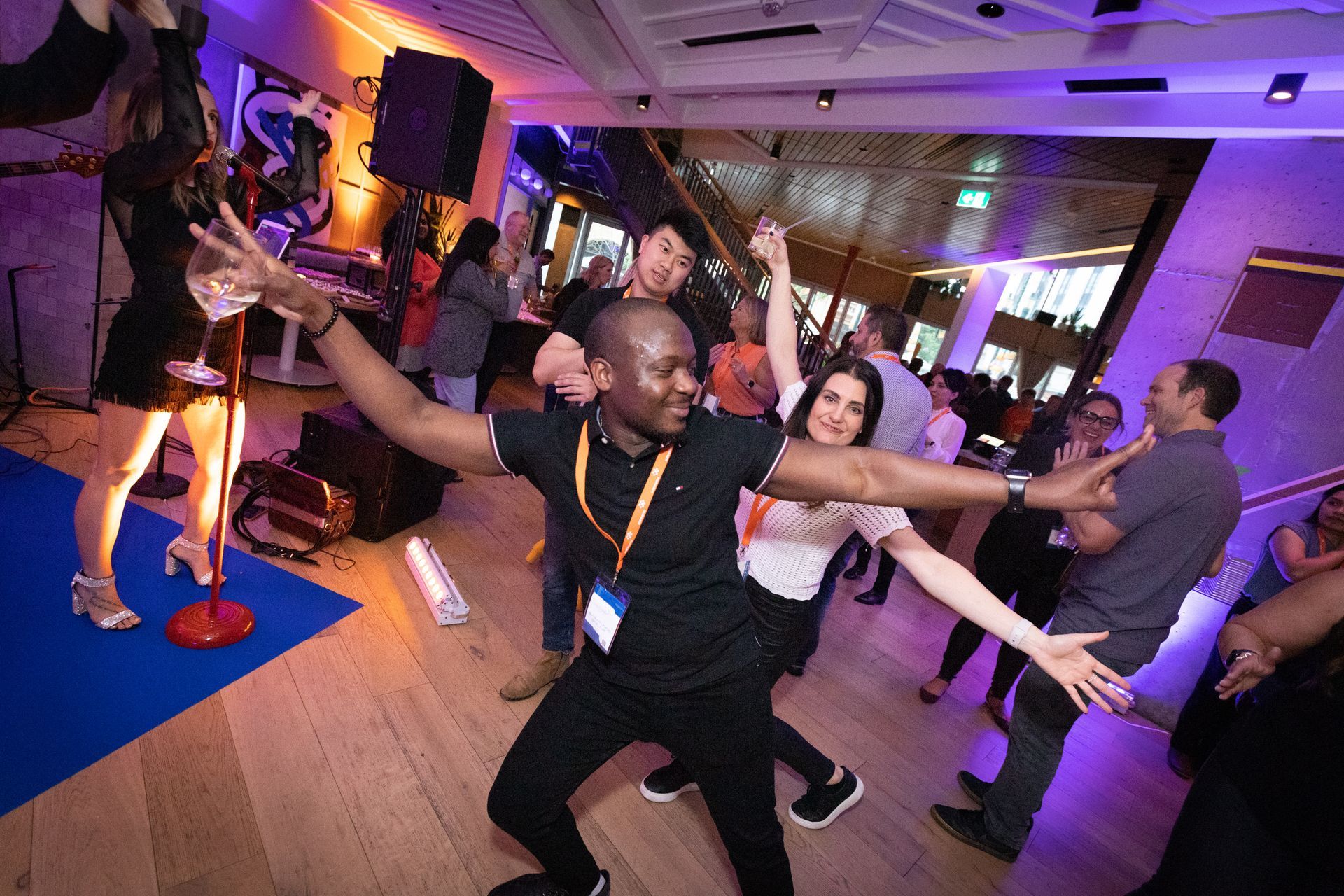 A group of people are dancing in a room with purple lights.