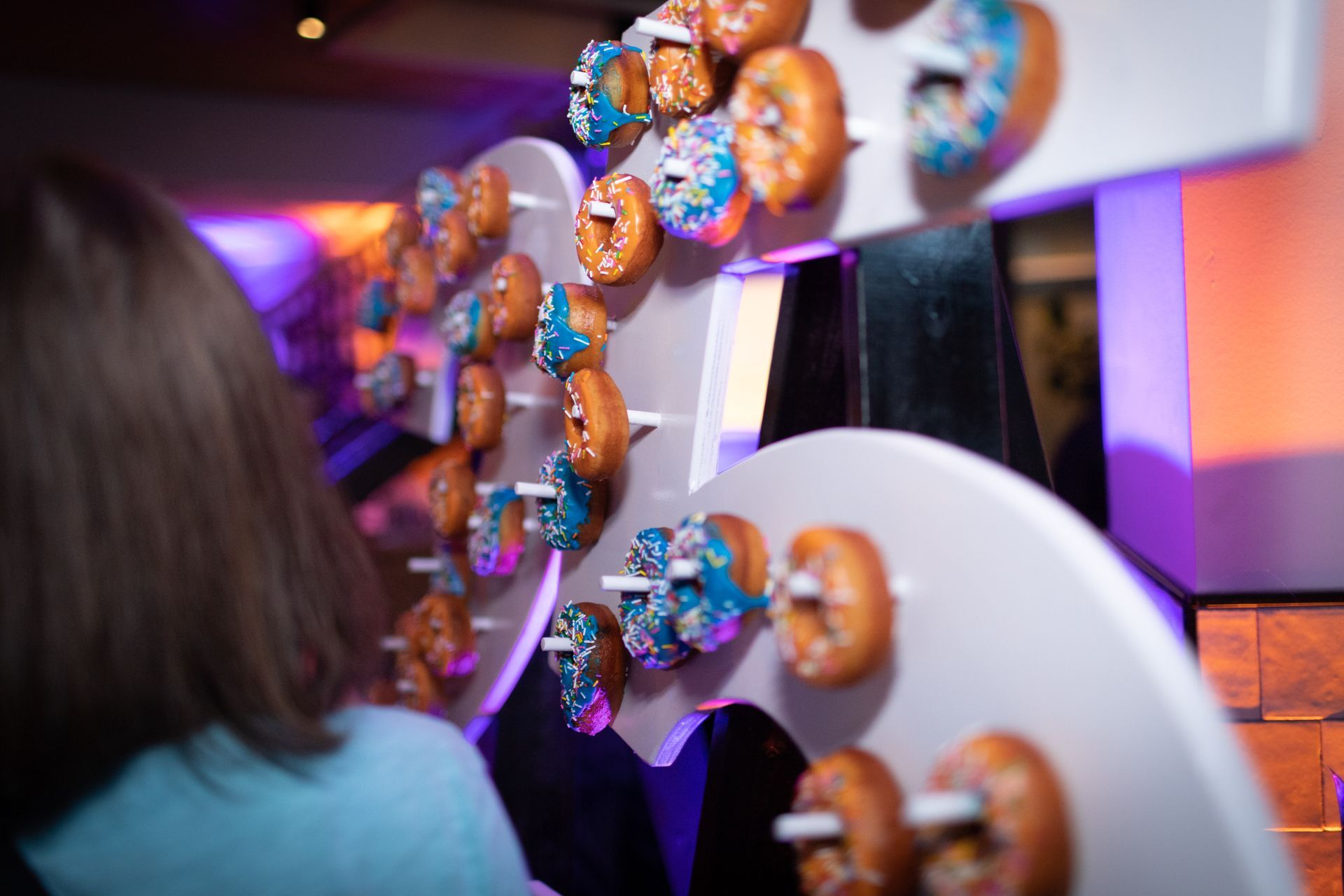 A woman is standing in front of a wall of donuts.