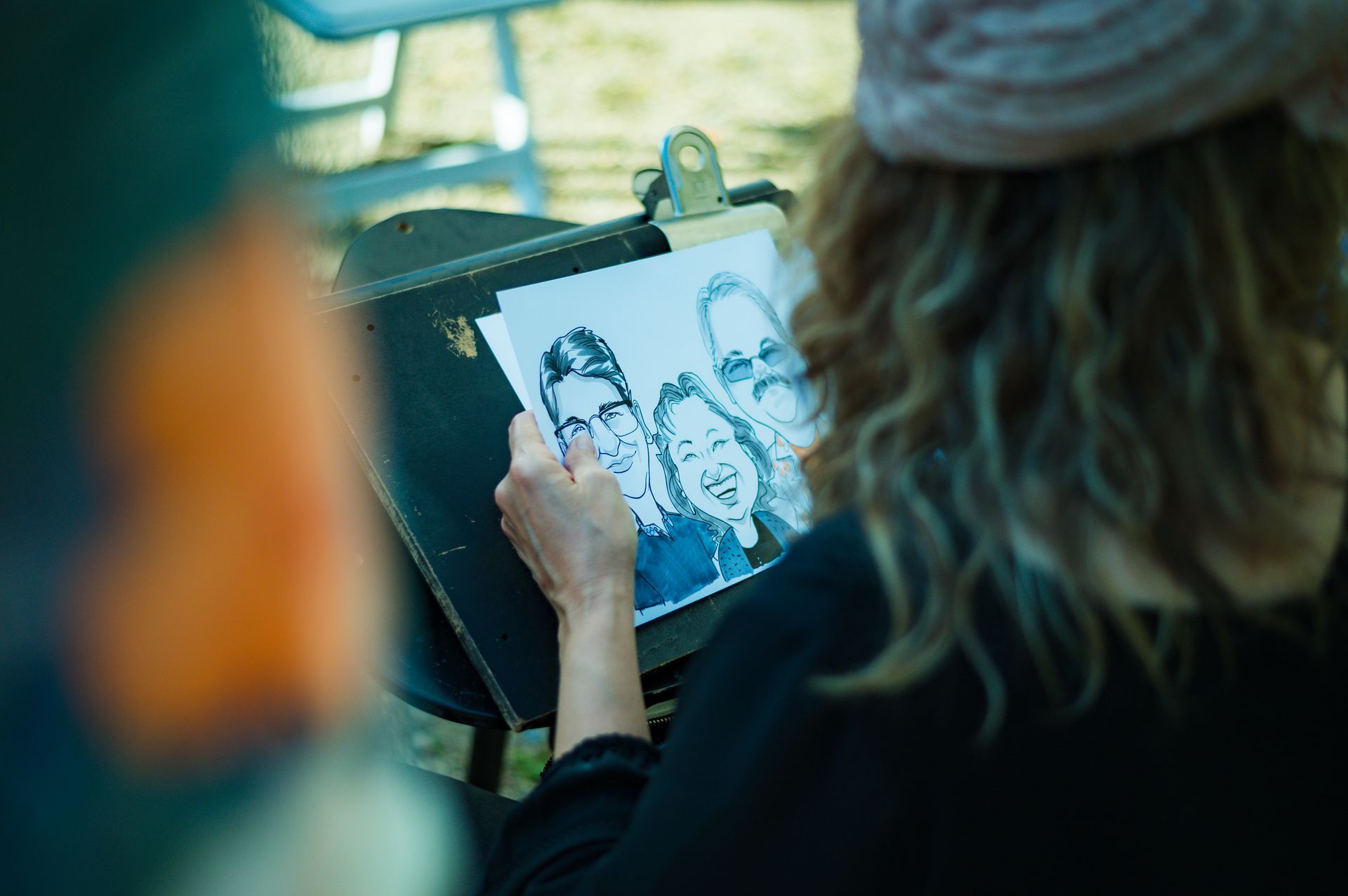 A woman is drawing a picture of a group of people on a clipboard.