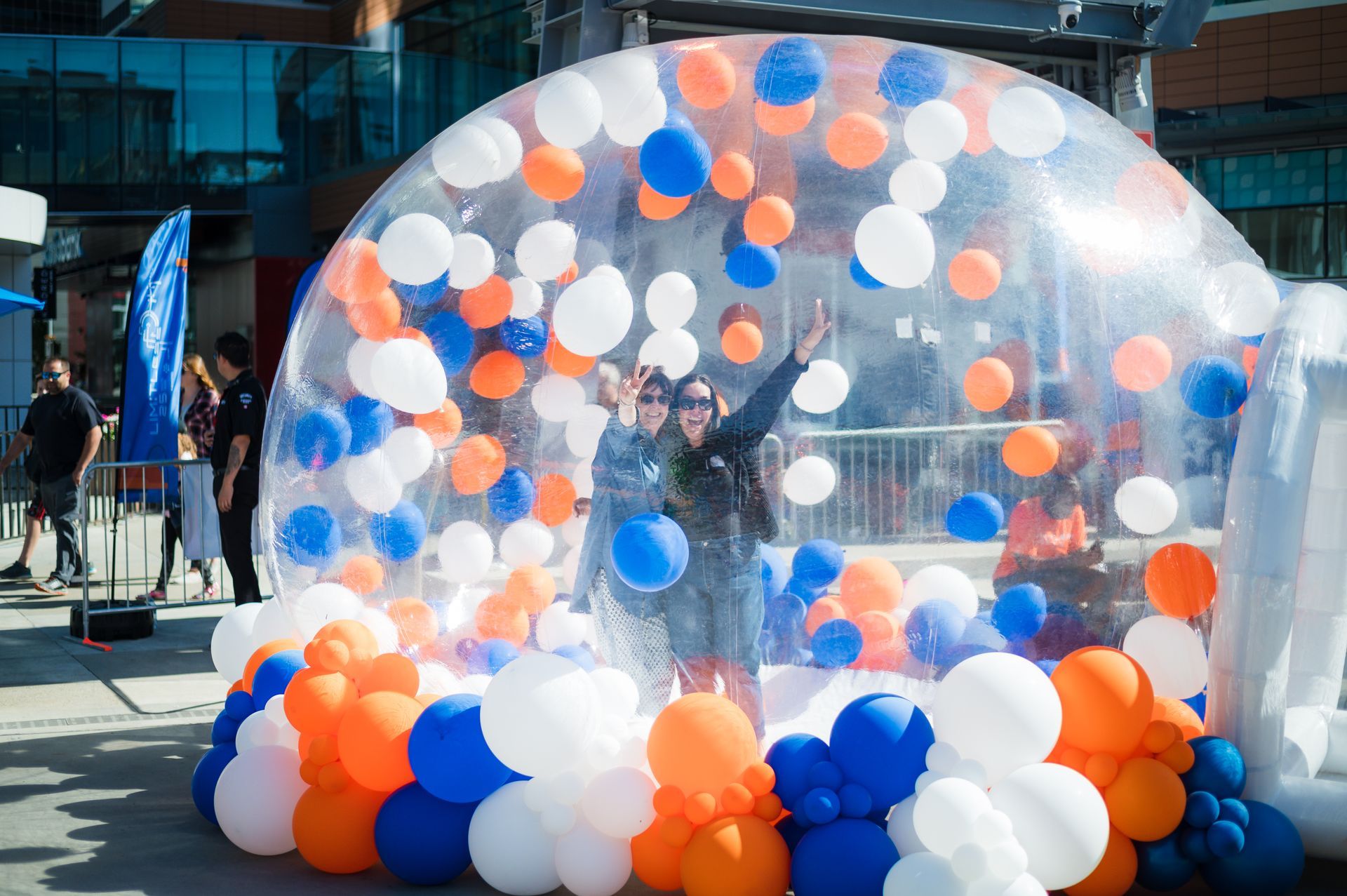 A woman is standing inside of a bubble filled with balloons.