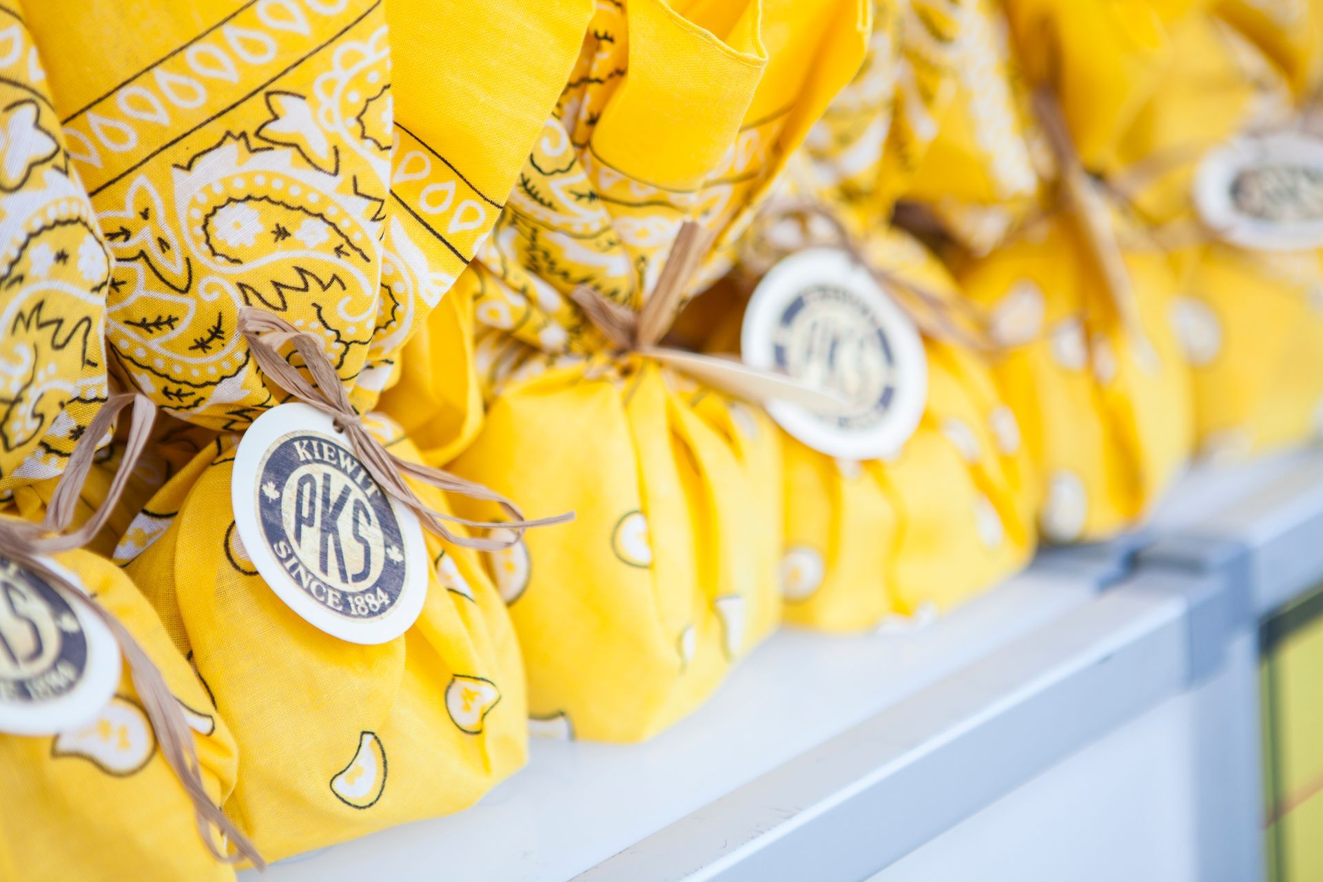 A row of yellow bandanas tied together with string on a shelf.