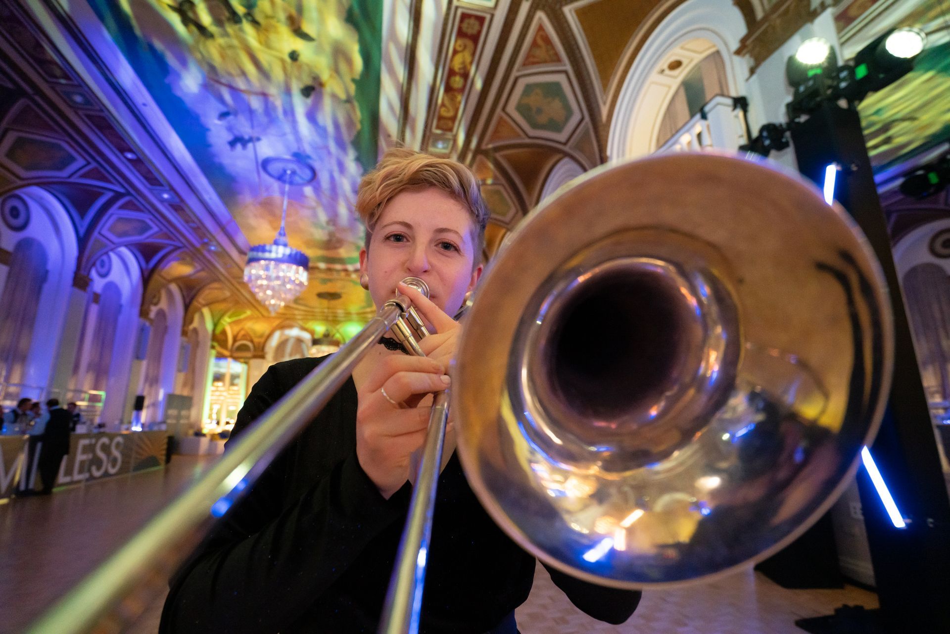 A woman is playing a trombone in a large room.