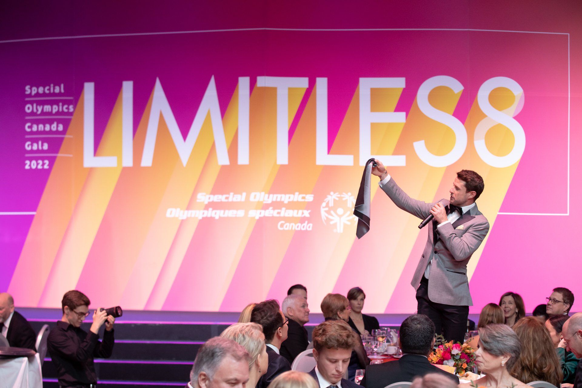 A man is holding a microphone in front of a sign that says limitless.