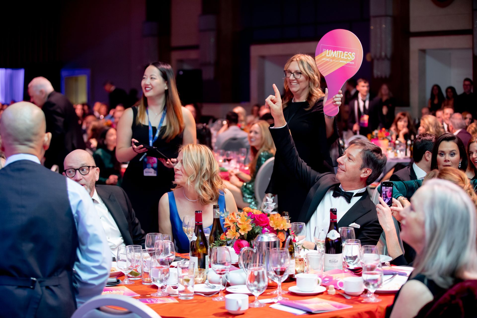 A group of people are sitting at tables at a dinner party.