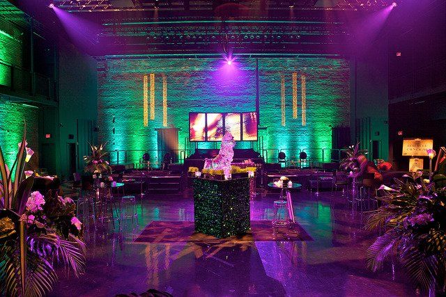 A large room with purple and green lights and a table in the middle of the room.