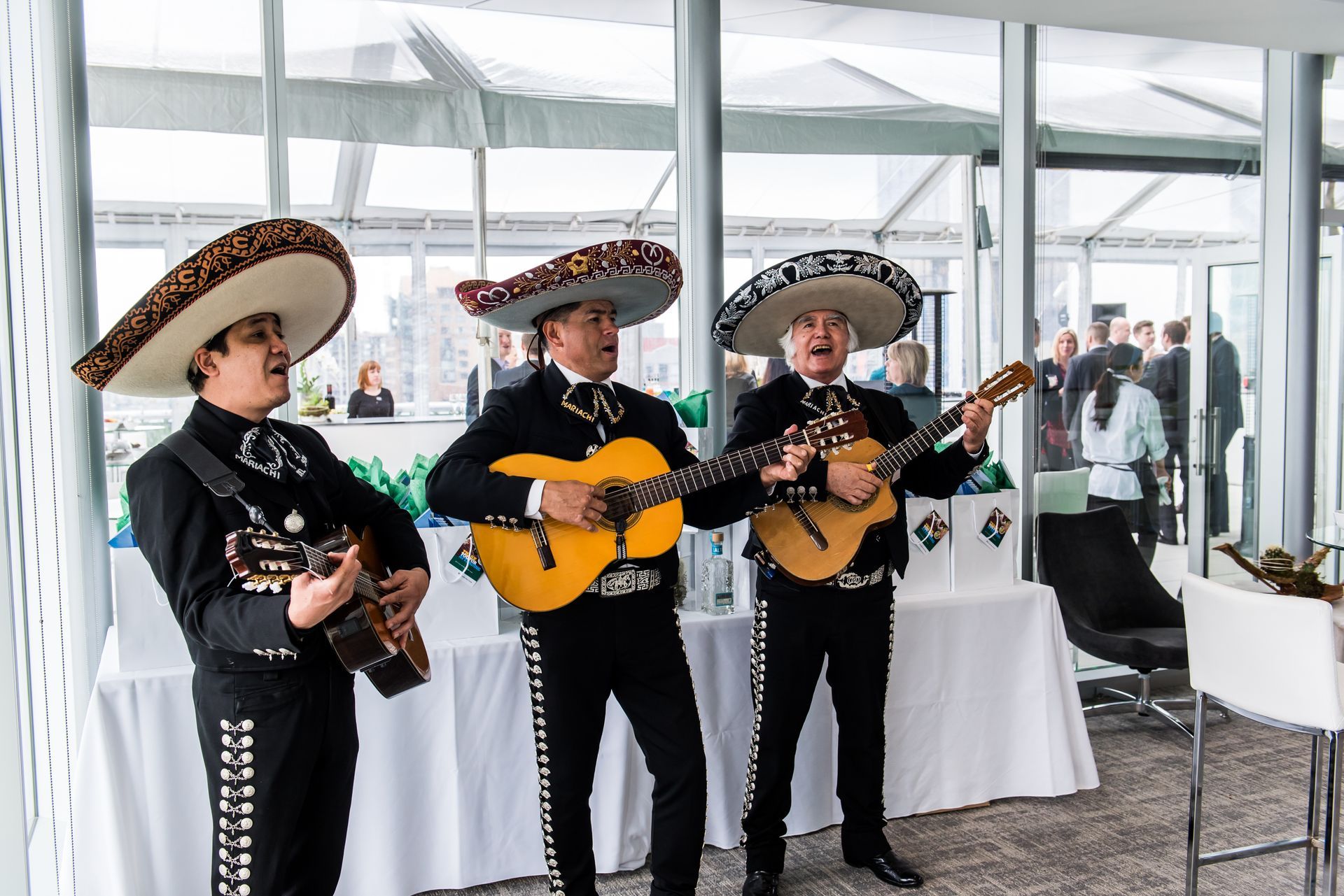 Three mariachi singers are playing guitars in a room.