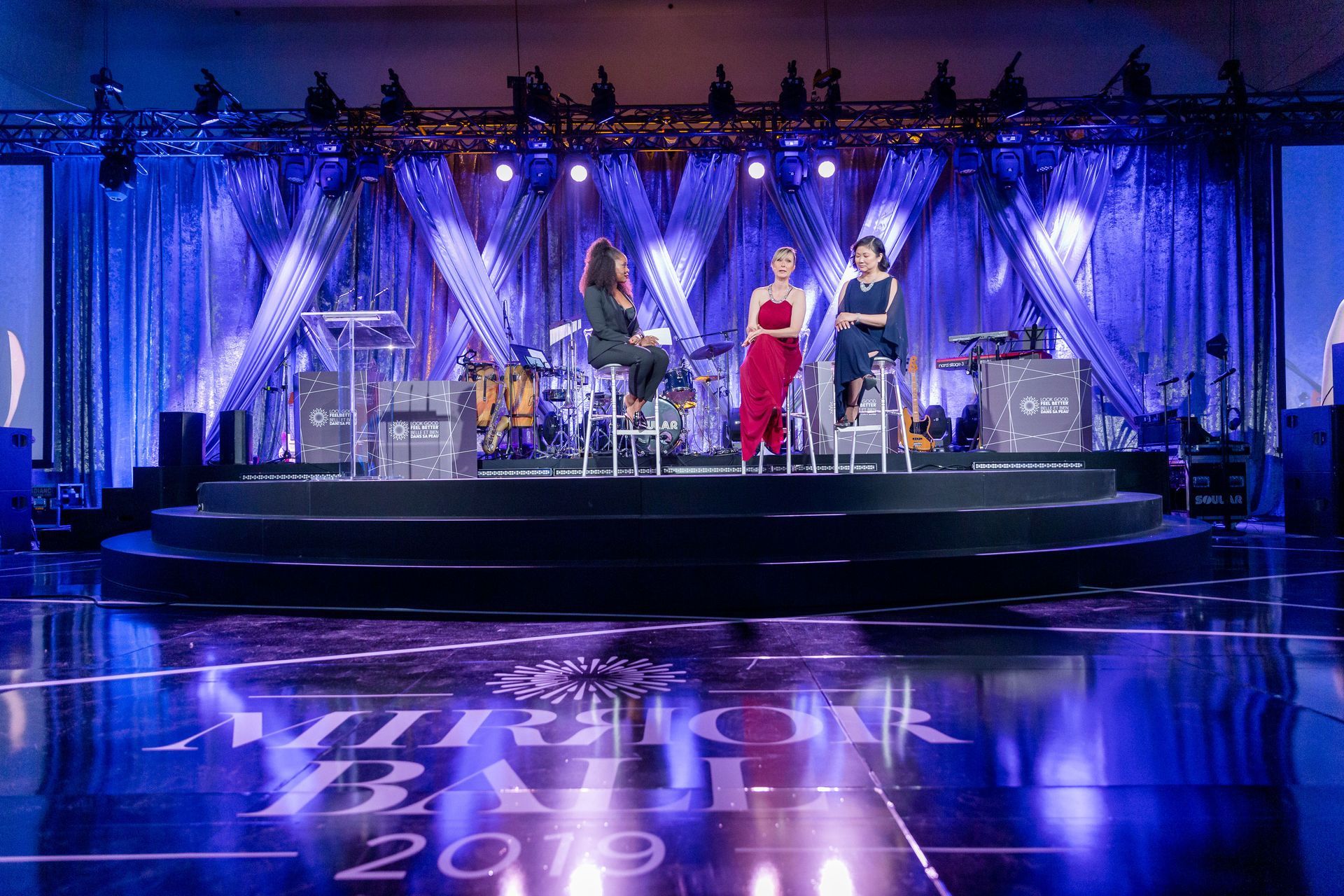 A group of women are standing on a stage with a band.