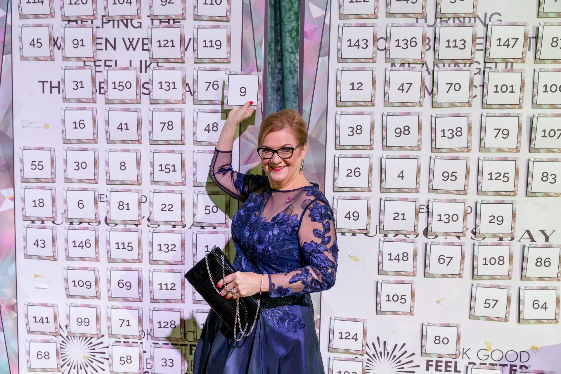 A woman in a blue dress is standing in front of a wall with numbers on it.