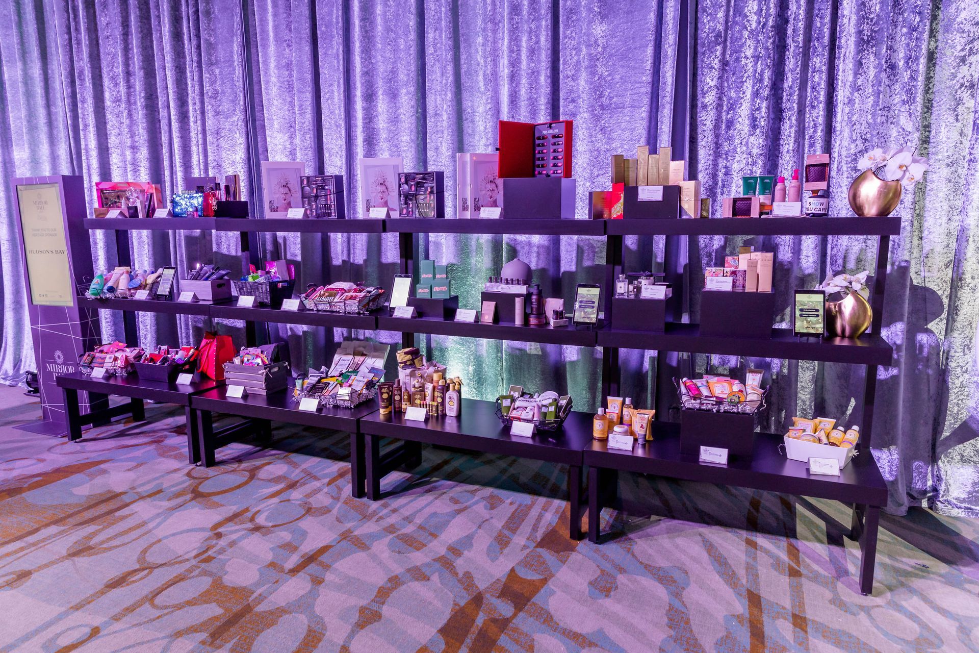 A display of various items on shelves in a room with a purple curtain behind them.