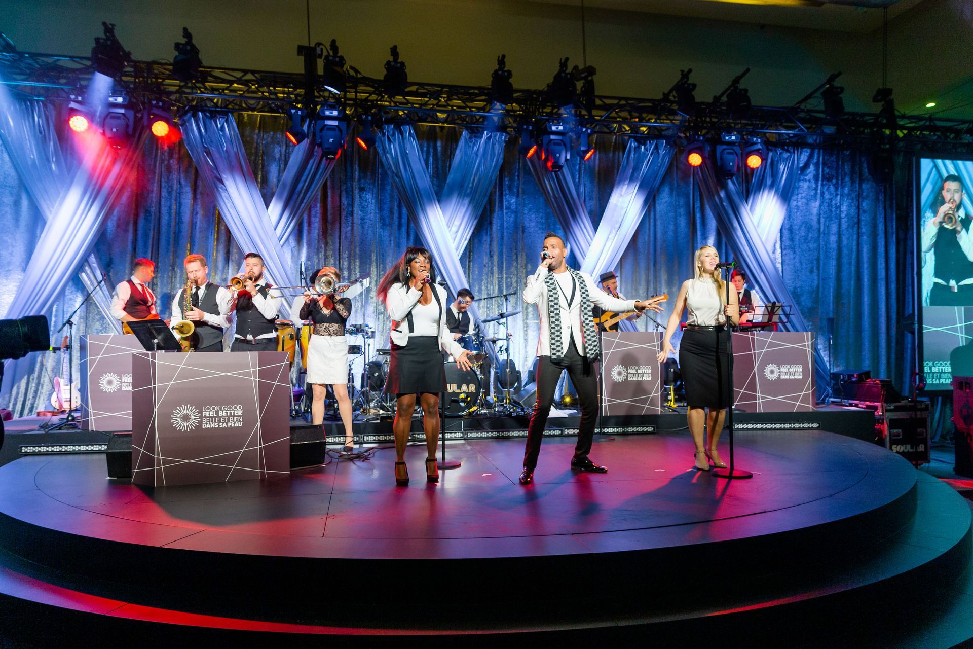 A group of people are standing on a stage singing into microphones.