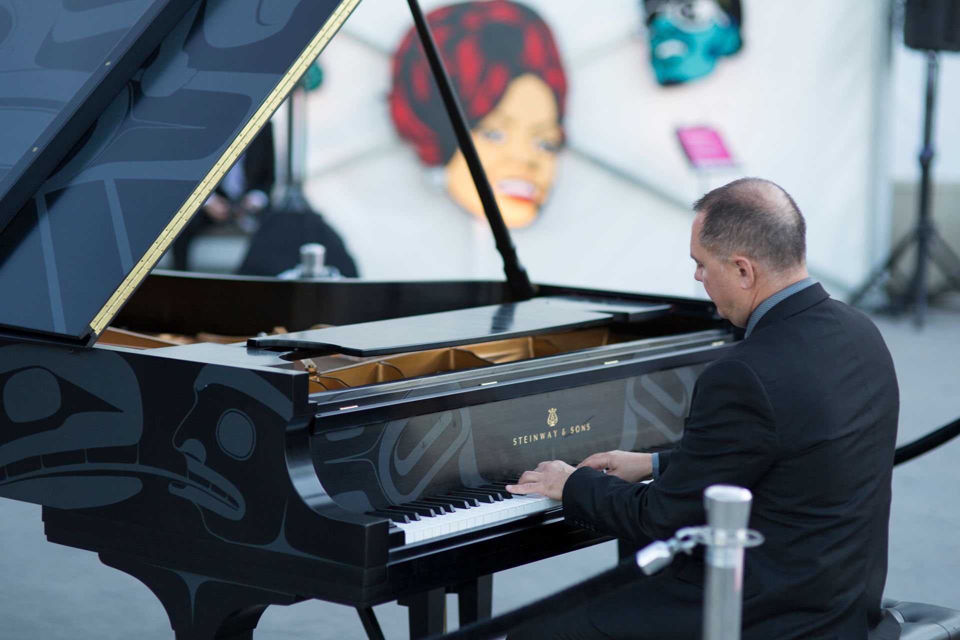 A man in a suit is playing a piano in front of a mural.