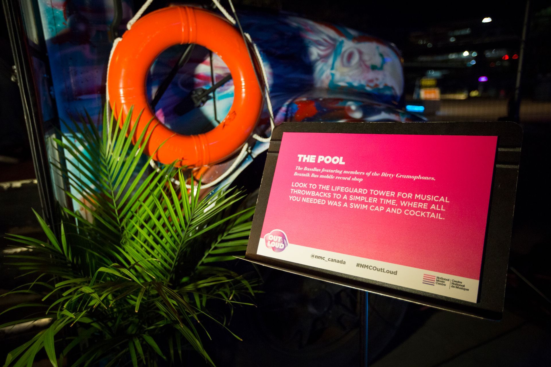 A life preserver is hanging on a wall next to a sign that says the pool.