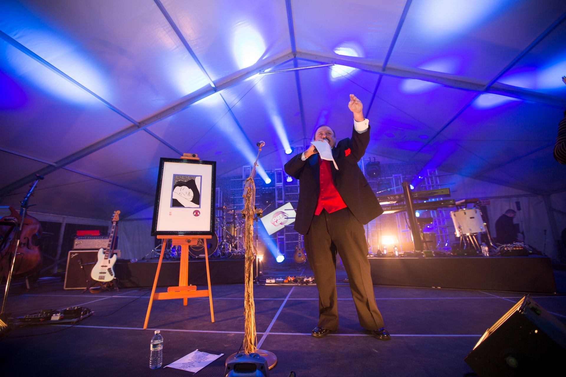 A man in a suit is standing on a stage holding a microphone.