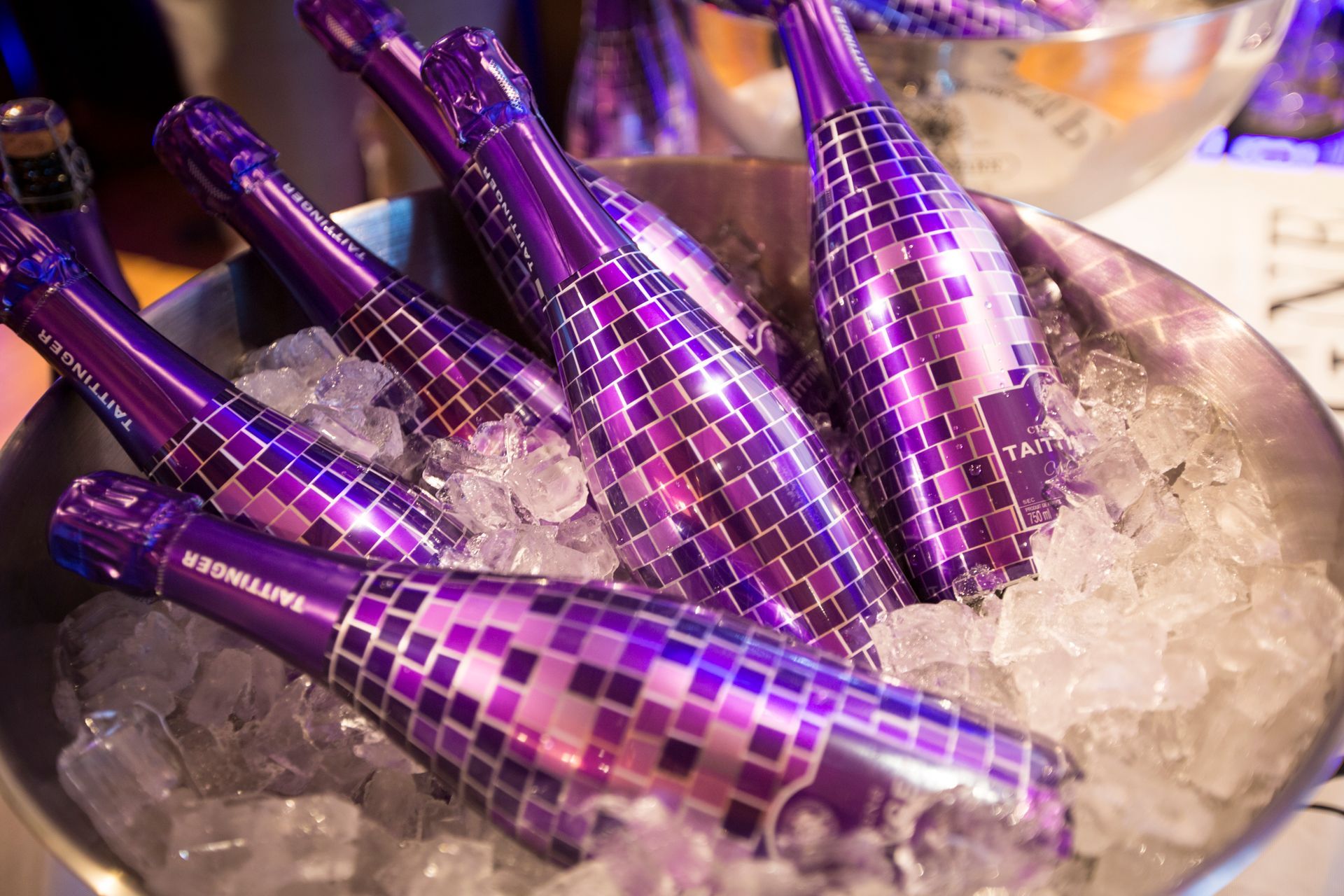 Purple bottles of champagne are sitting in a bucket of ice.
