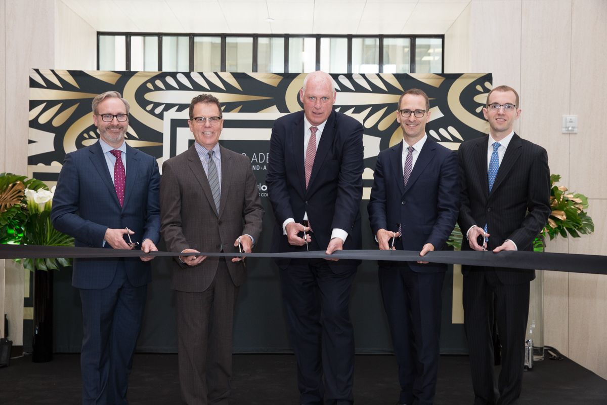 A group of men in suits are cutting a black ribbon
