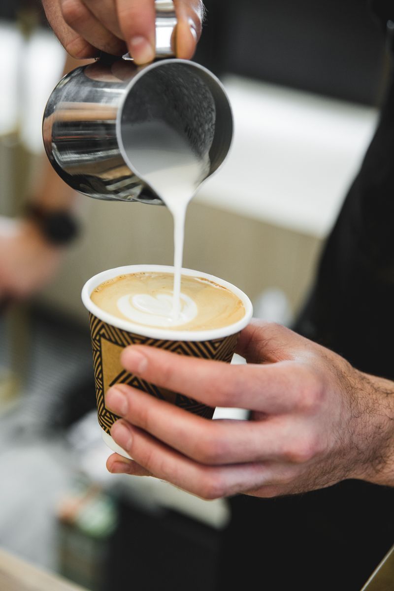 A person is pouring milk into a cup of coffee