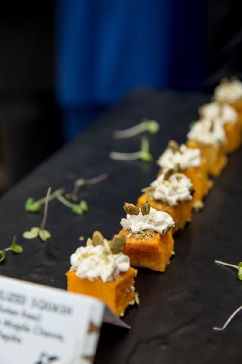 A row of small pieces of food with whipped cream on top