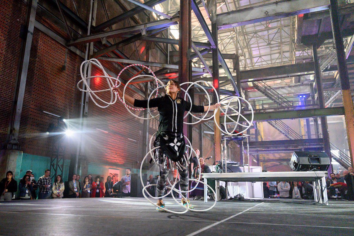 A man is jumping rope in a warehouse in front of a crowd.