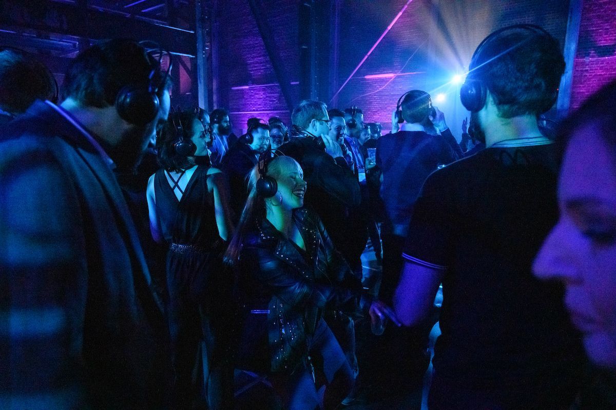 A group of people are standing in a dark room wearing headphones.