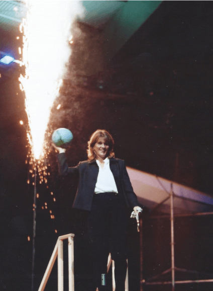 A man in a suit is holding a ball in front of a fireworks display