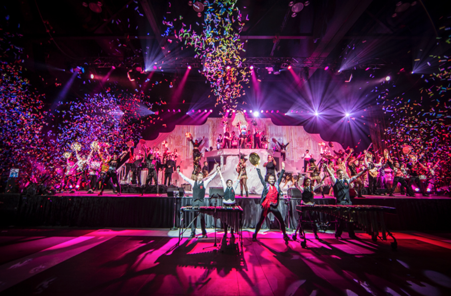 A group of people are standing on a stage with confetti falling from the ceiling.