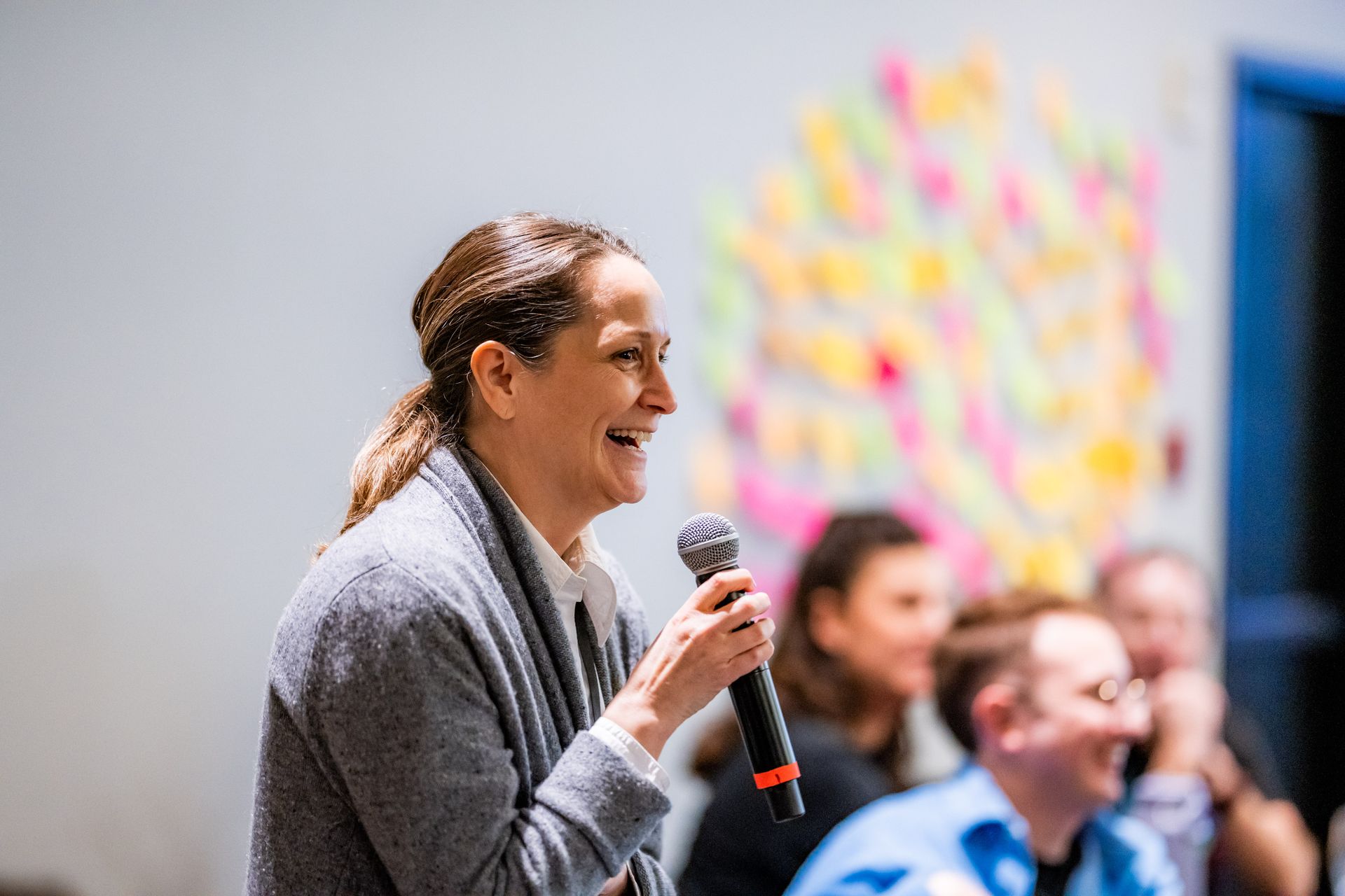 A woman is holding a microphone in front of a group of people.