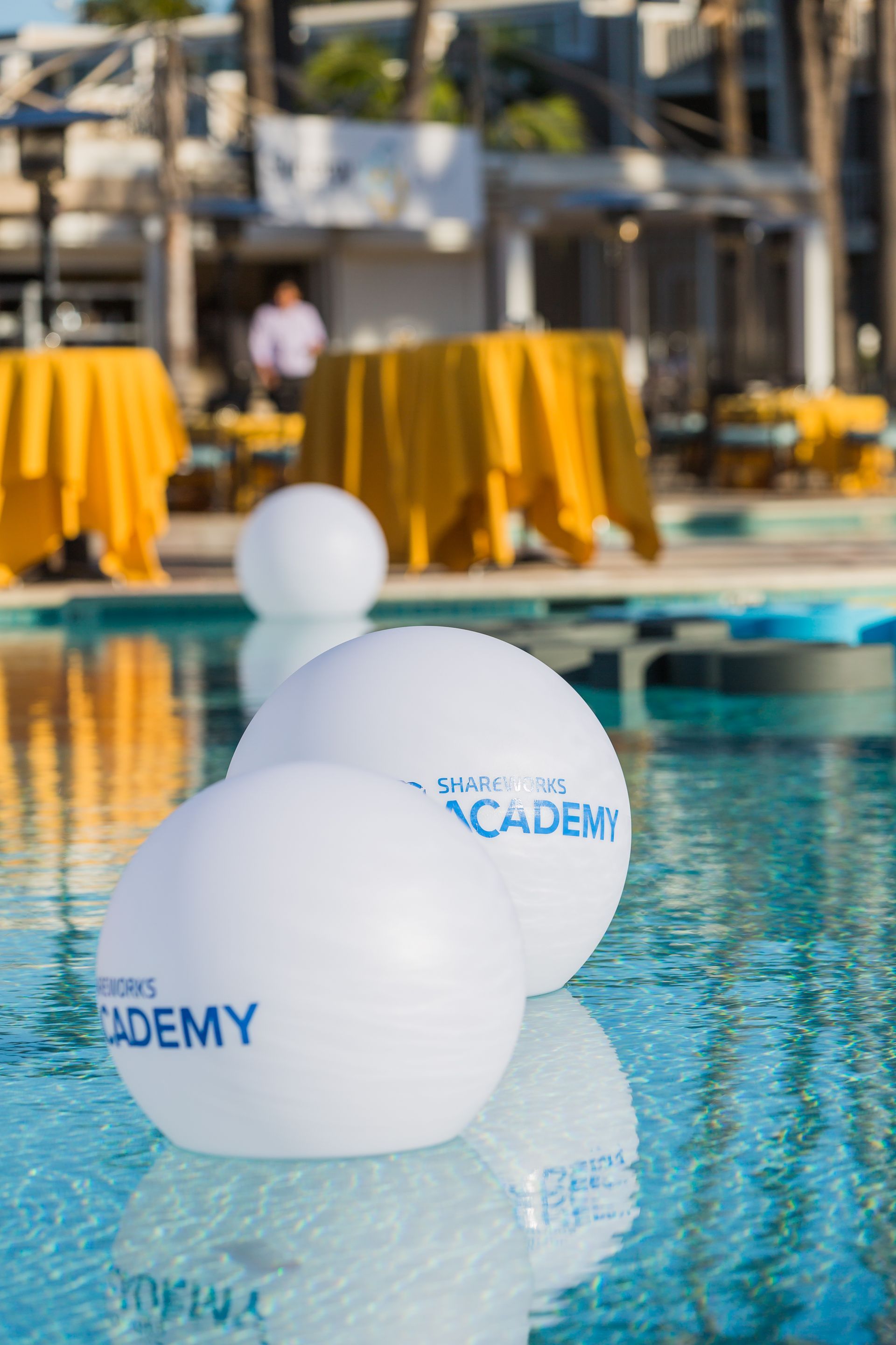 White floating spheres in a pool with blue text 