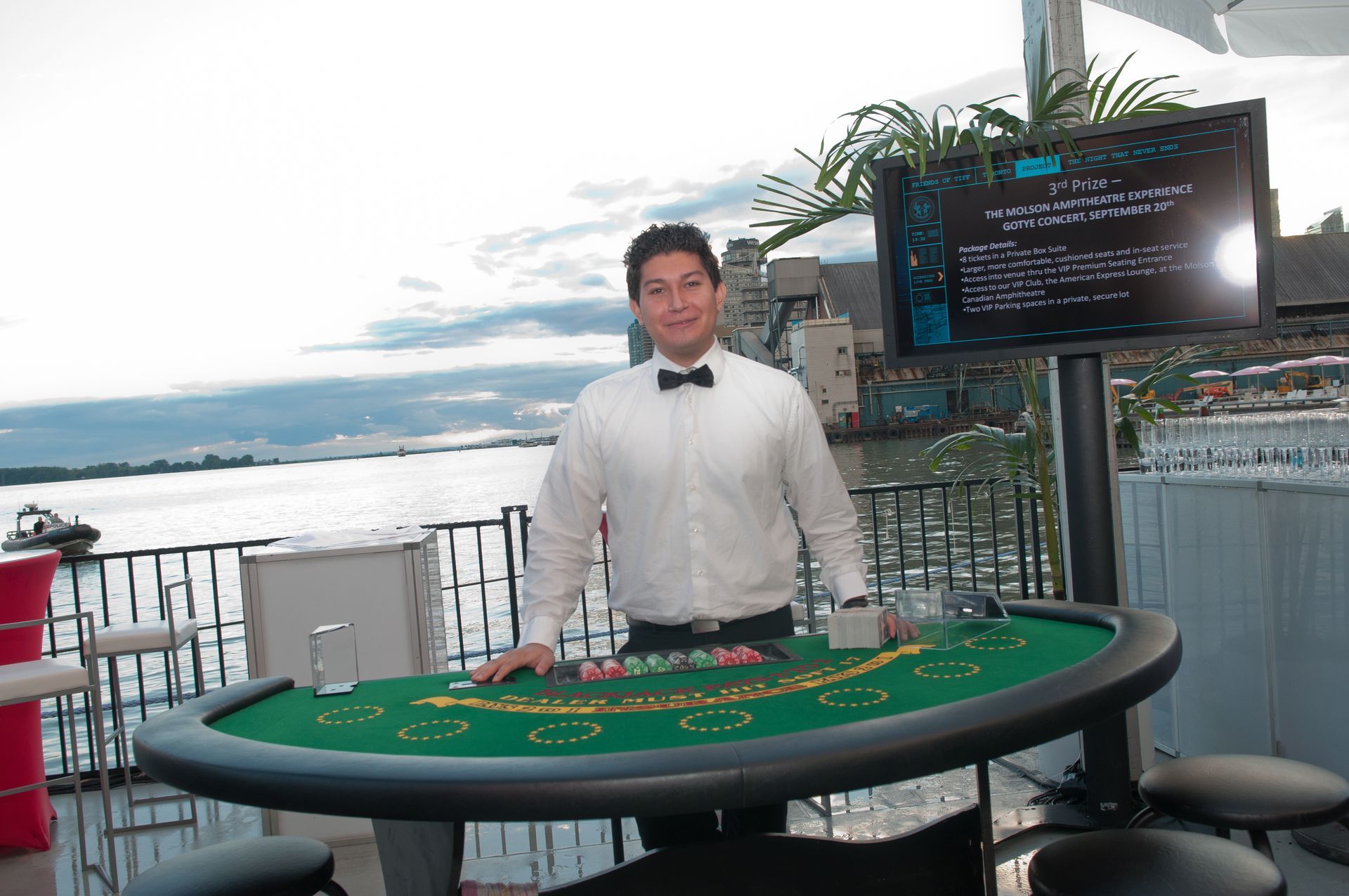 A man in a bow tie is standing in front of a poker table.