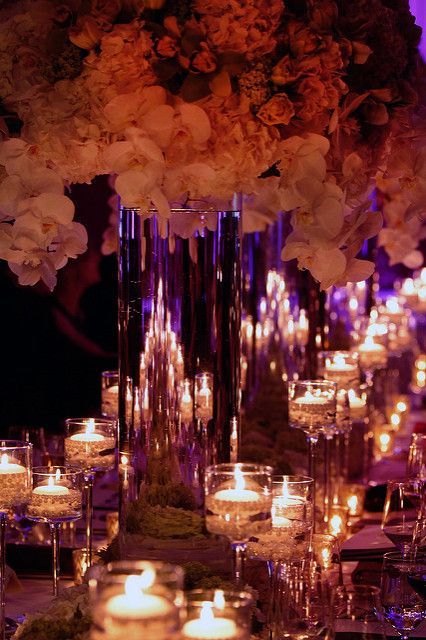 A table with lots of candles and flowers on it.