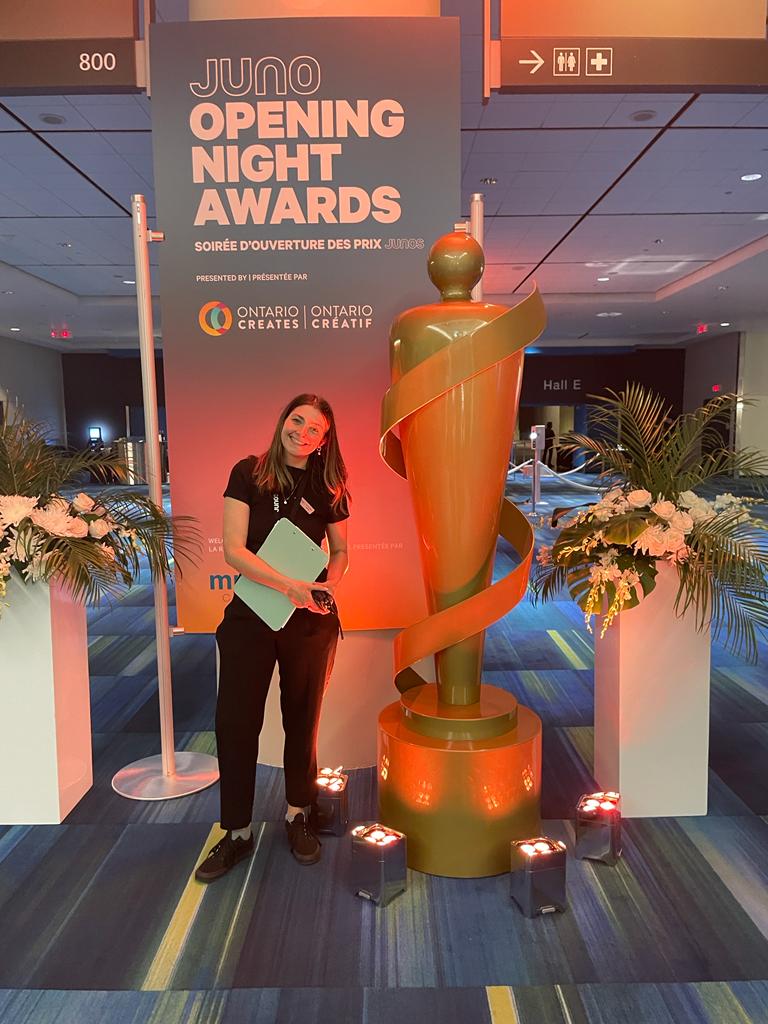 A woman is standing next to a statue in front of a sign that says opening night awards.