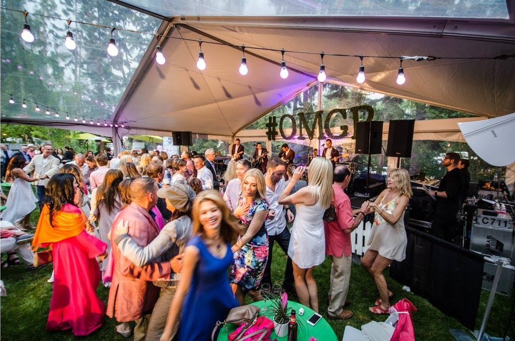 A large group of people are dancing under a tent.
