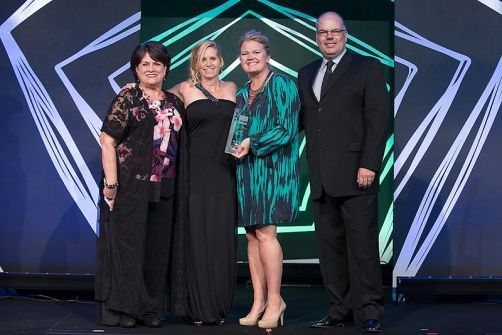 A group of people standing next to each other on a stage holding an award.