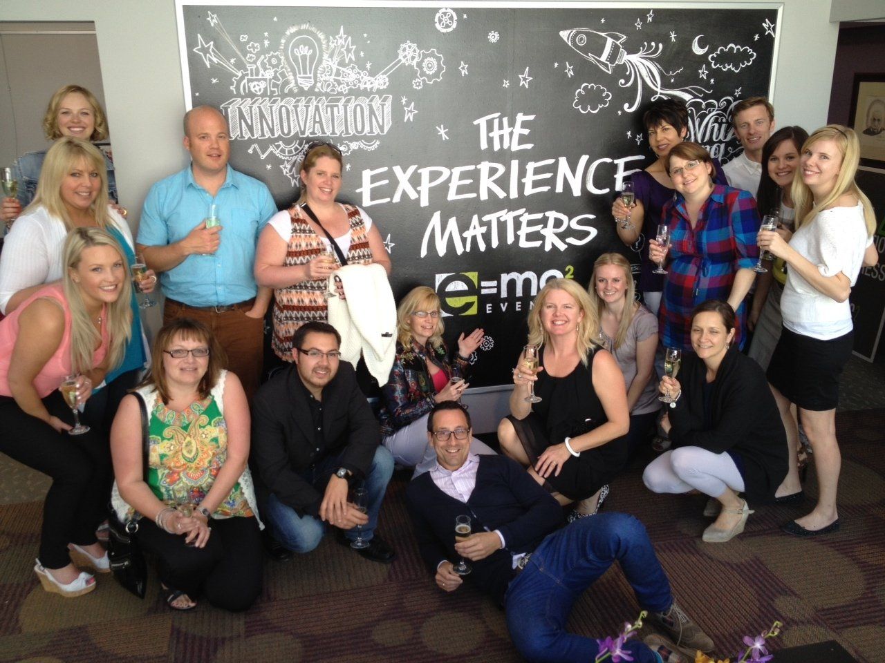 A group of people posing in front of a sign that says the experience matters