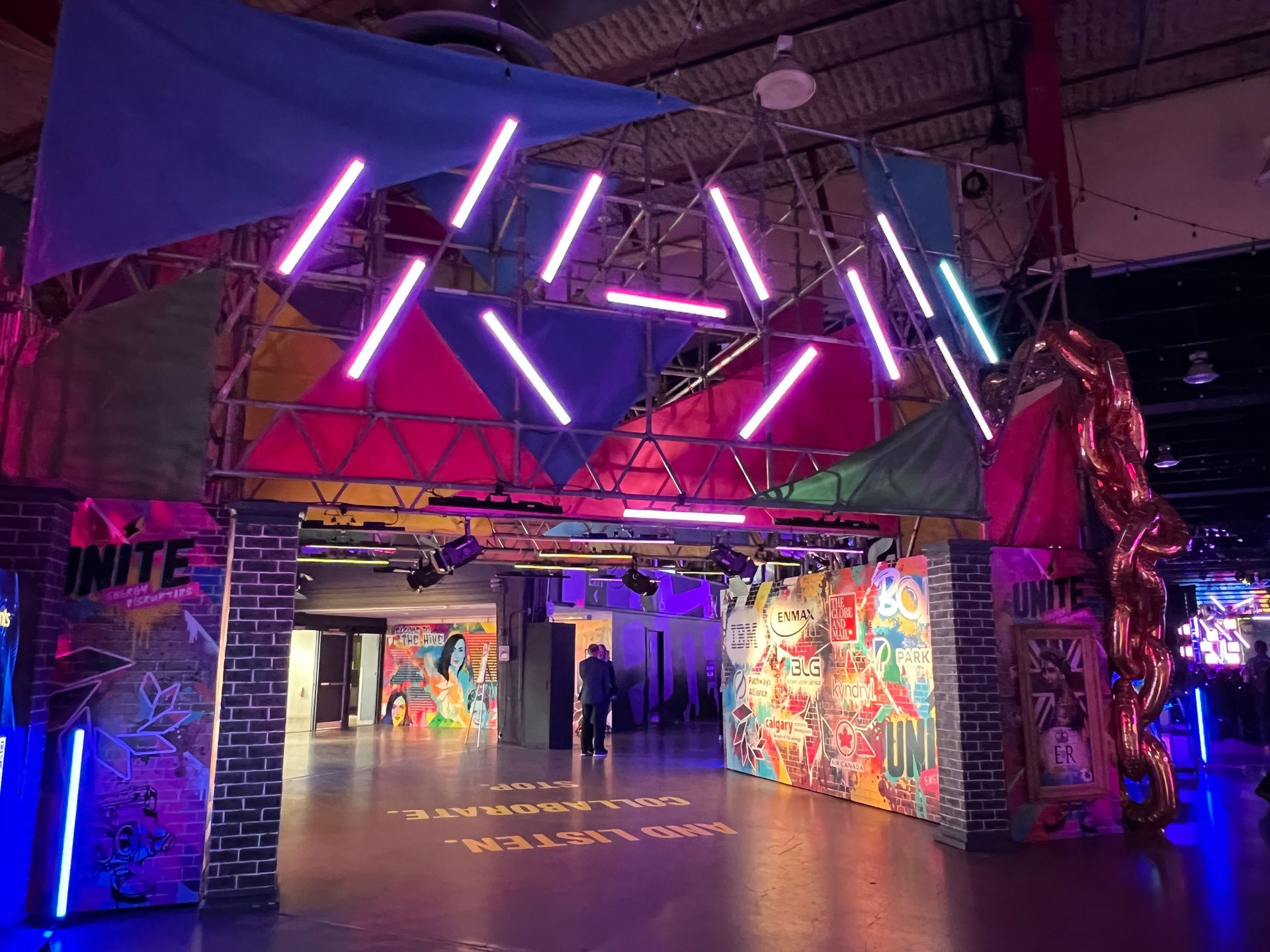A large room with a lot of neon lights and graffiti on the walls.