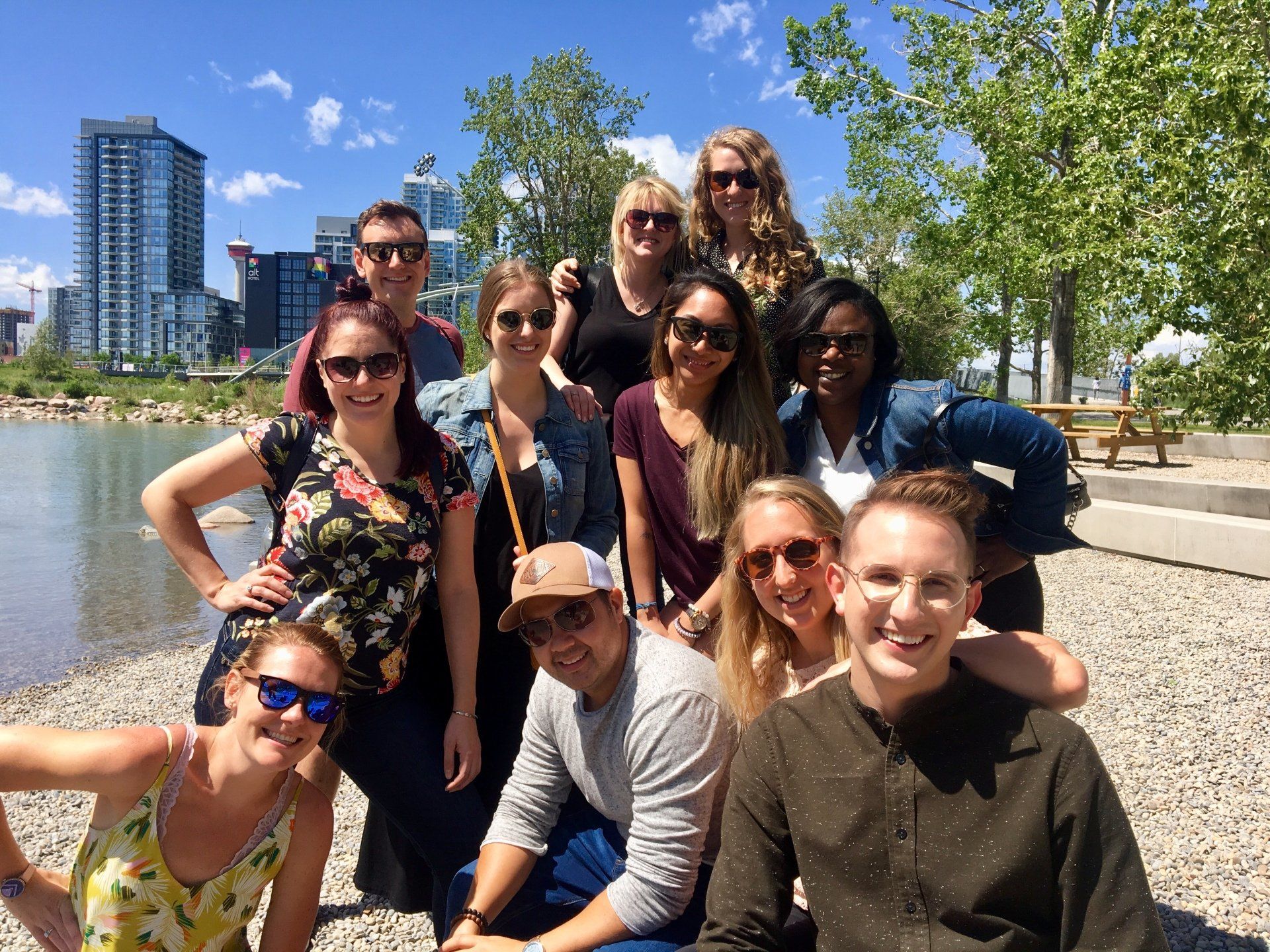 A group of people are posing for a picture in front of a body of water.