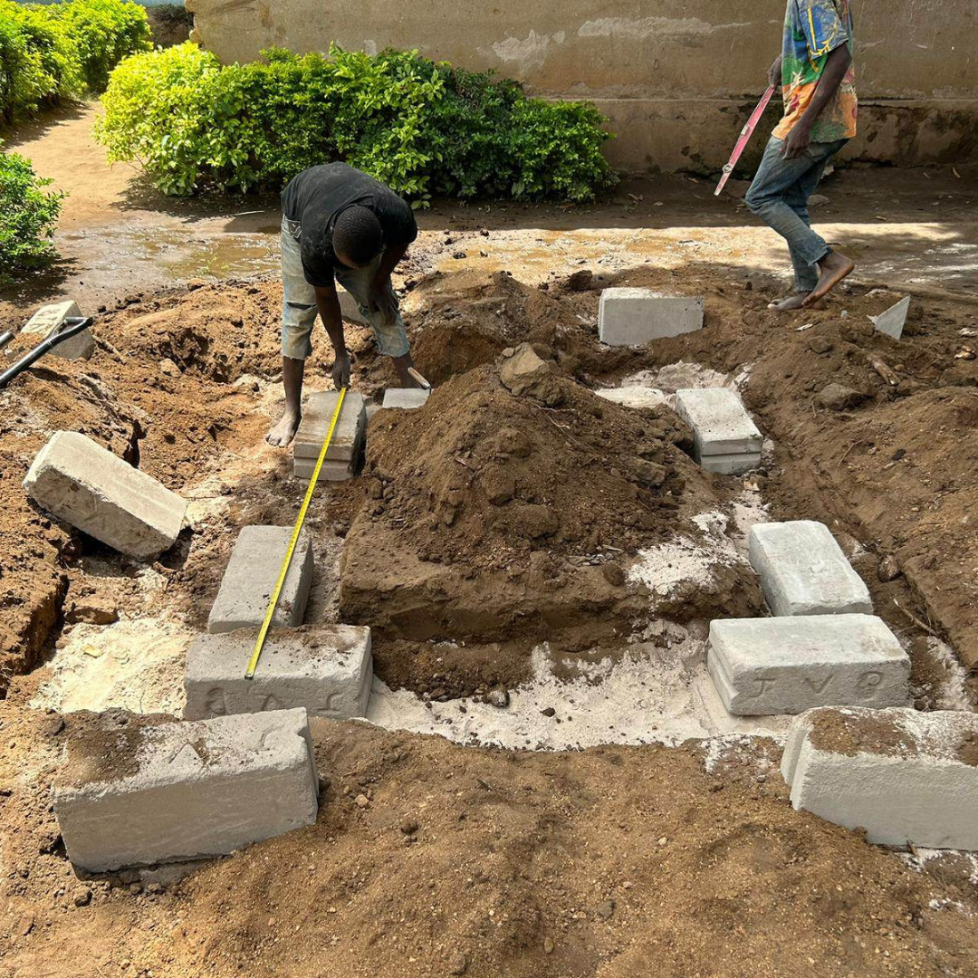 A man is measuring a pile of dirt with a tape measure.