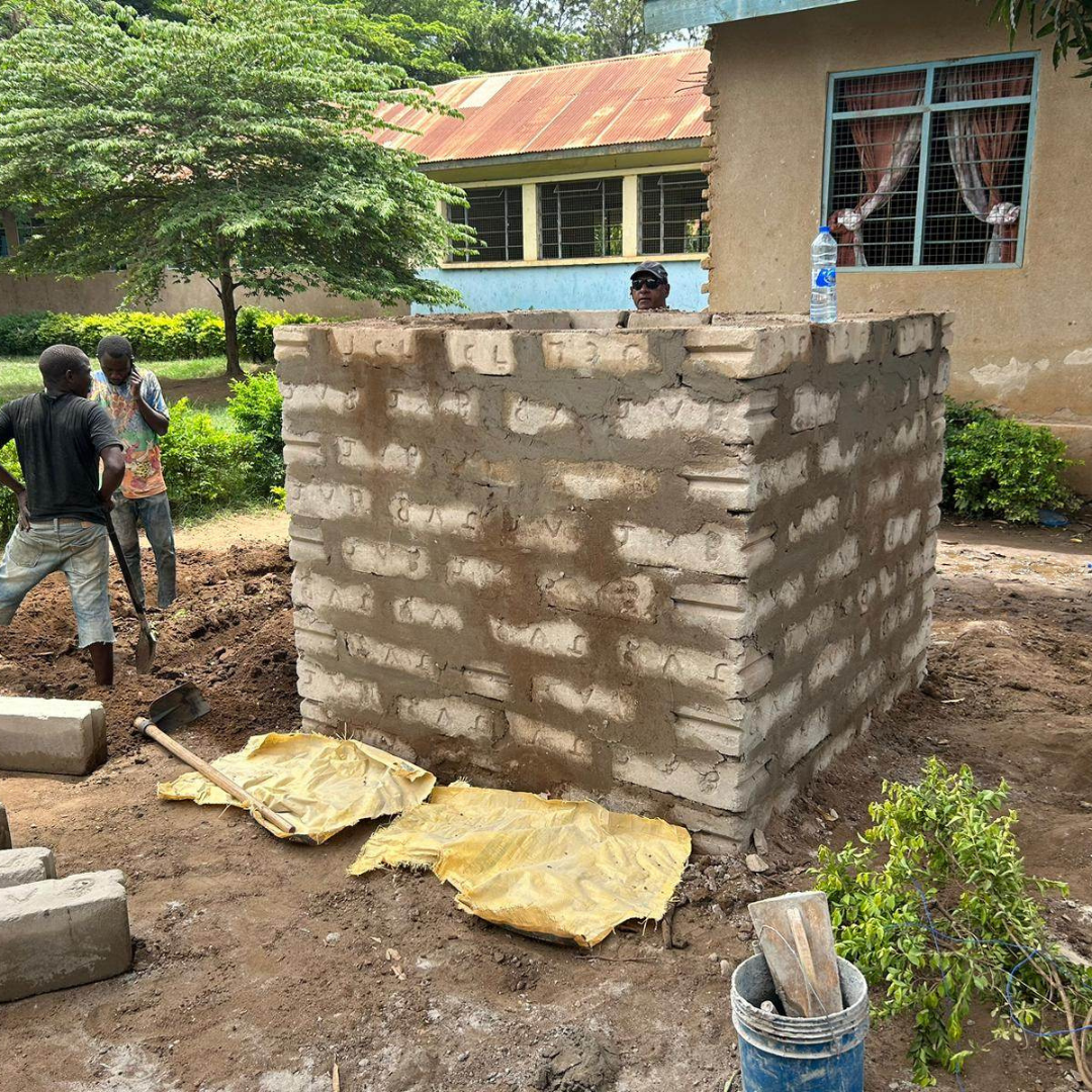 A group of people are working on a brick wall in front of a house.