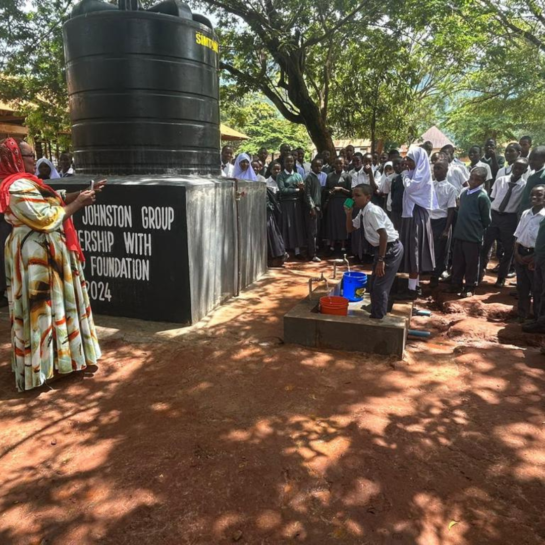A group of people are standing around a large black tank.