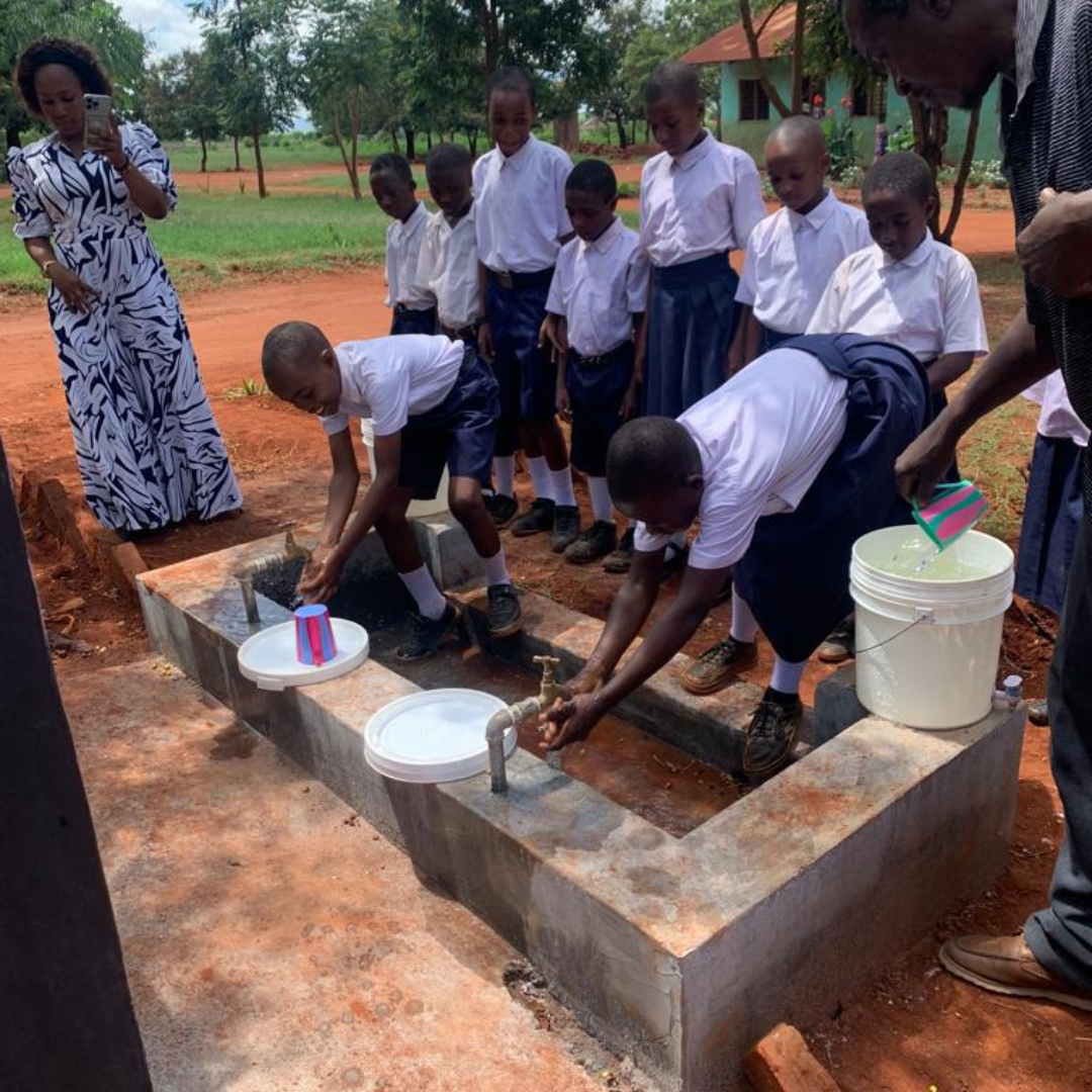 A group of children are washing their hands at a well