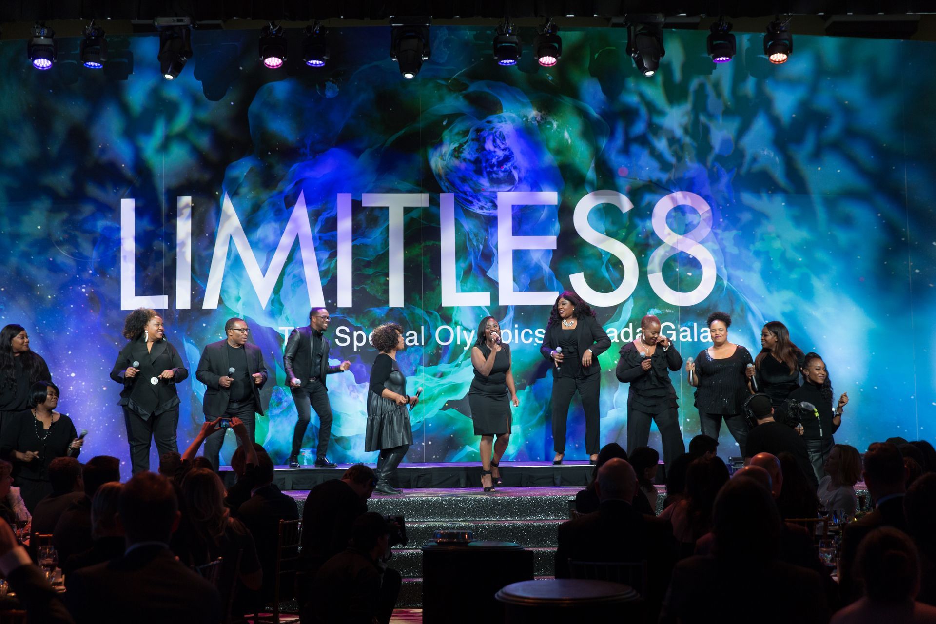 A group of people are standing on a stage in front of a sign that says limitless