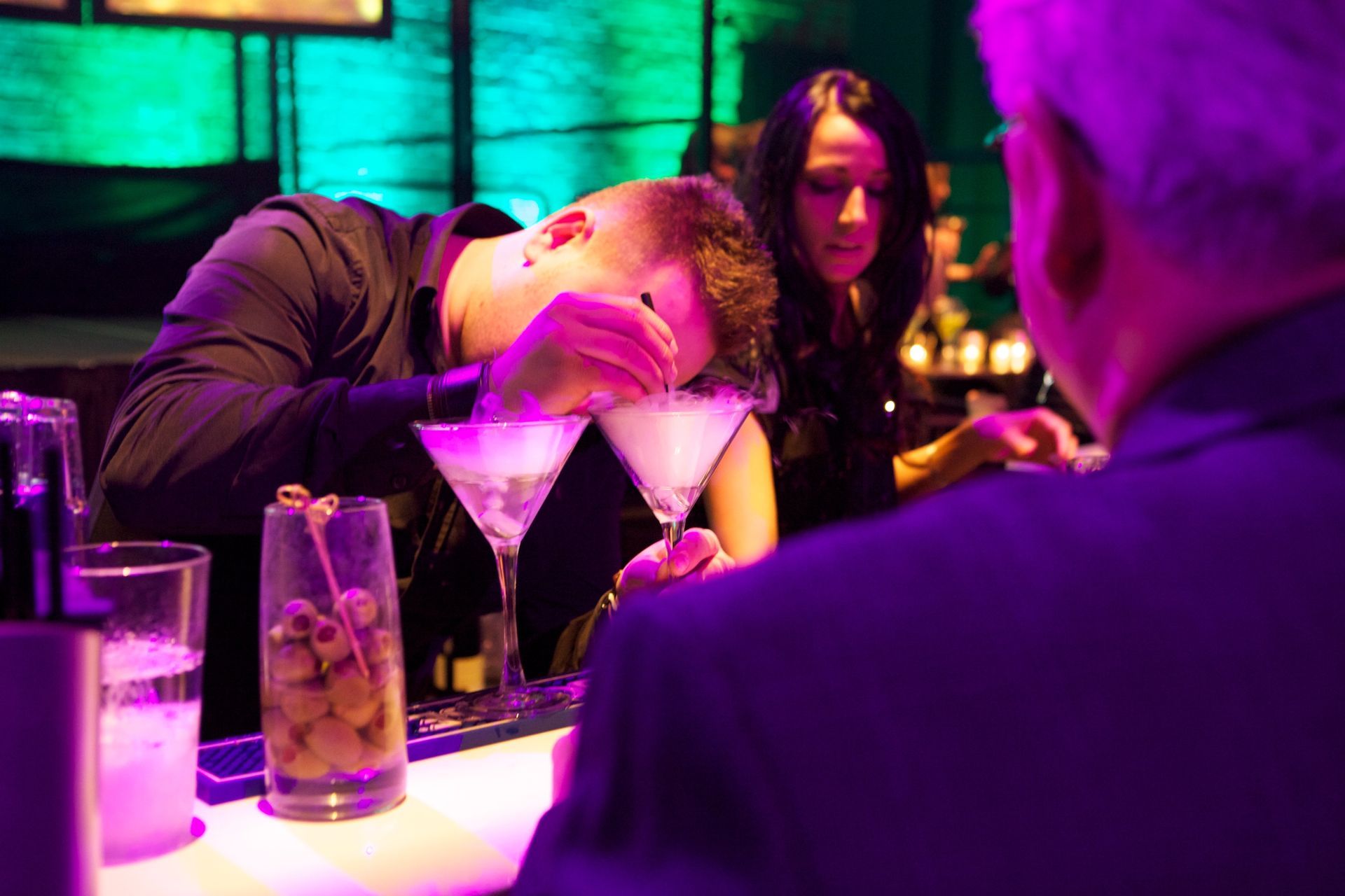A man is sitting at a bar with his head in a martini glass.