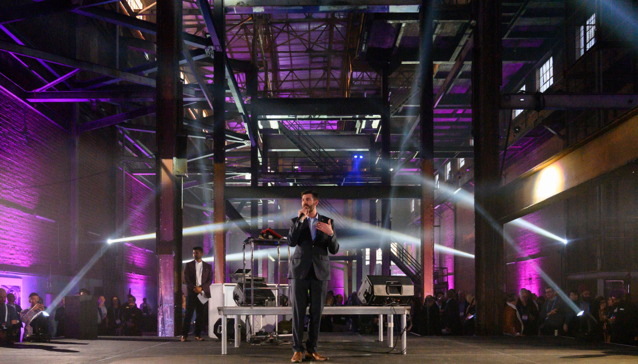 A man in a suit is standing on a stage in front of a crowd.