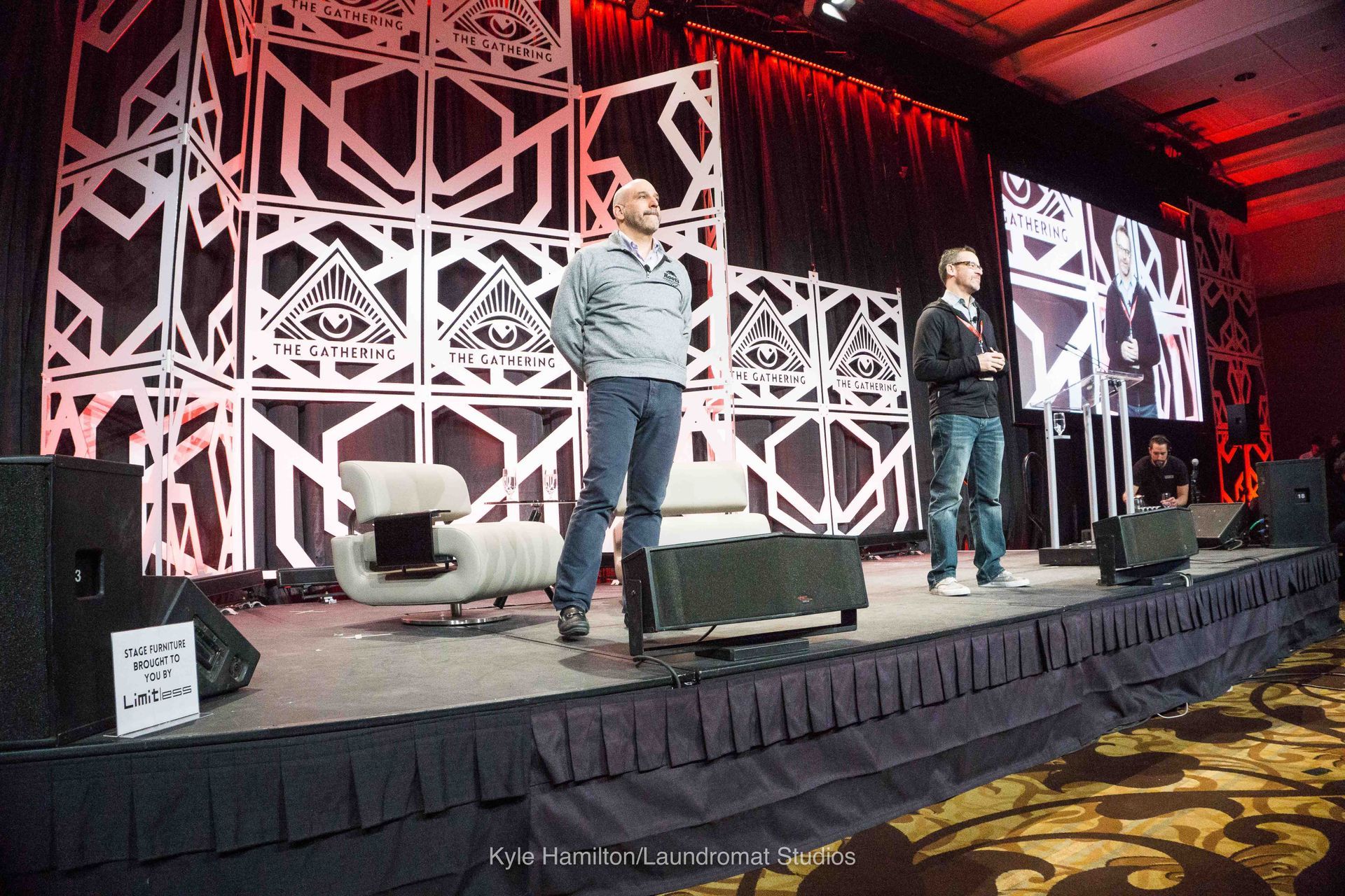 Two men are standing on a stage talking to each other.