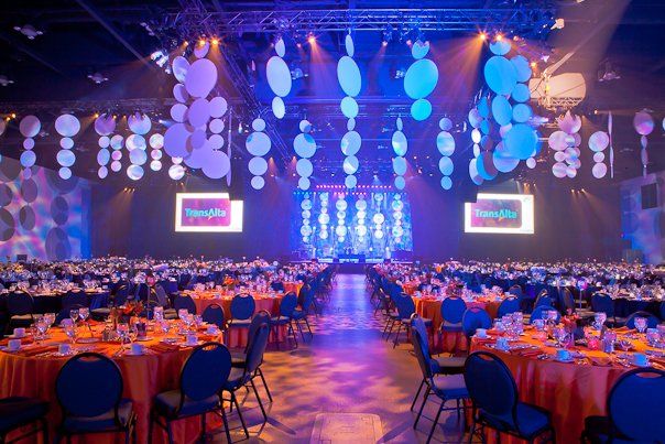 A large room filled with tables and chairs and balloons hanging from the ceiling.