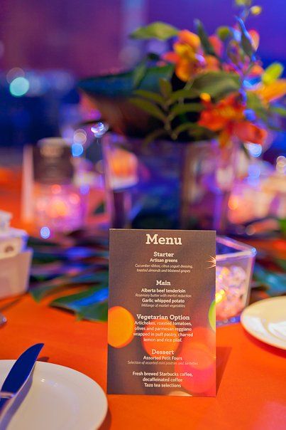 A menu is sitting on a table next to a vase of flowers.