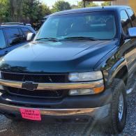 Black Chevrolet SUV parked outdoors with a pink sale tag on the front bumper
