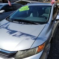 Silver sedan parked outdoors with neon green sale sign on the windshield