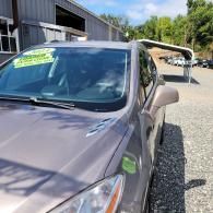 Purple car parked beside a gravel lot near a building, with a solar panel in the background