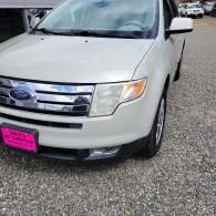 White Ford SUV parked on gravel, front view with pink license plate cover