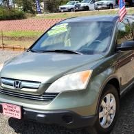 Green Honda SUV parked outdoors with a small American flag on the roof.